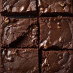 Close-up de brownie partido mostrando casquinha brilhante e interior fudgy.