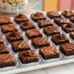 Mini brownies para festa em forminhas de papel, com brigadeiro, confeitos e fios de chocolate.
