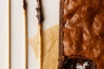 Palito no centro do brownie com migalhas úmidas, indicando o ponto certo