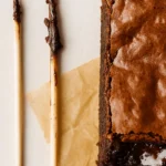 Palito no centro do brownie com migalhas úmidas, indicando o ponto certo