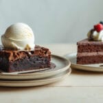Brownie com sorvete ao lado de uma fatia de bolo de chocolate com chantilly e frutas