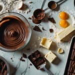 Cenário bagunçado de cozinha com ingredientes espalhados, incluindo farinha derramada, ovos quebrados, chocolate e manteiga, ilustrando os erros que sabotam o sabor do brownie