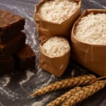 foto de brownies ao lado de sacos de farinha sobre mesa enfarinhada
