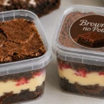 Dois potes transparentes de brownie com camadas de creme de chocolate, um aberto e outro fechado