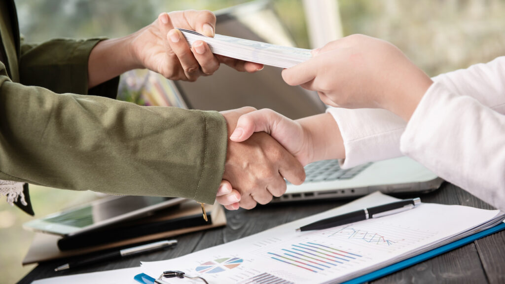 conseguindo-credito-para-confeitaria Mãos apertadas em acordo, representando uma confeiteira conseguindo crédito ou investimento graças à boa gestão financeira de seu negócio.