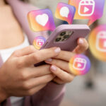 Mulher segurando um celular, representando o planejamento do marketing para vender doces no Instagram.