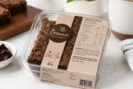 Brownie artesanal embalado com rótulo detalhado, tabela nutricional e alergênicos sobre bancada clara.