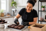 Confeiteira caseira organiza brownies em cozinha limpa, referência a alvará sanitário para confeitaria MEI