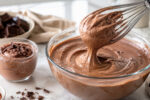 Mousse de chocolate que não pesa sendo misturada no bowl, com textura aerada, chocolate e porção pronta na bancada.