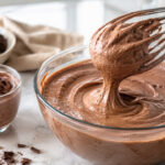 Mousse de chocolate que não pesa sendo misturada no bowl, com textura aerada, chocolate e porção pronta na bancada.