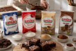 Embalagens de açúcar mostram qual açúcar usar no brownie, com bowls, chocolate e brownies na bancada.