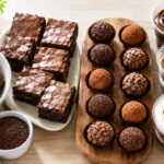 Doces para vender organizados em bancada clara, com brigadeiros, brownies, trufas e bolos no pote em luz matinal.
