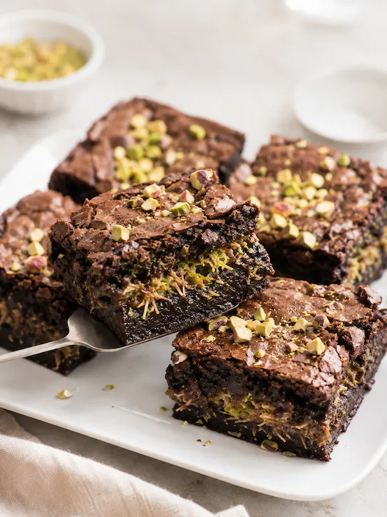 Pedaço de brownie Dubai mostrando recheio de pistache com kataifi entre camadas densas de chocolate